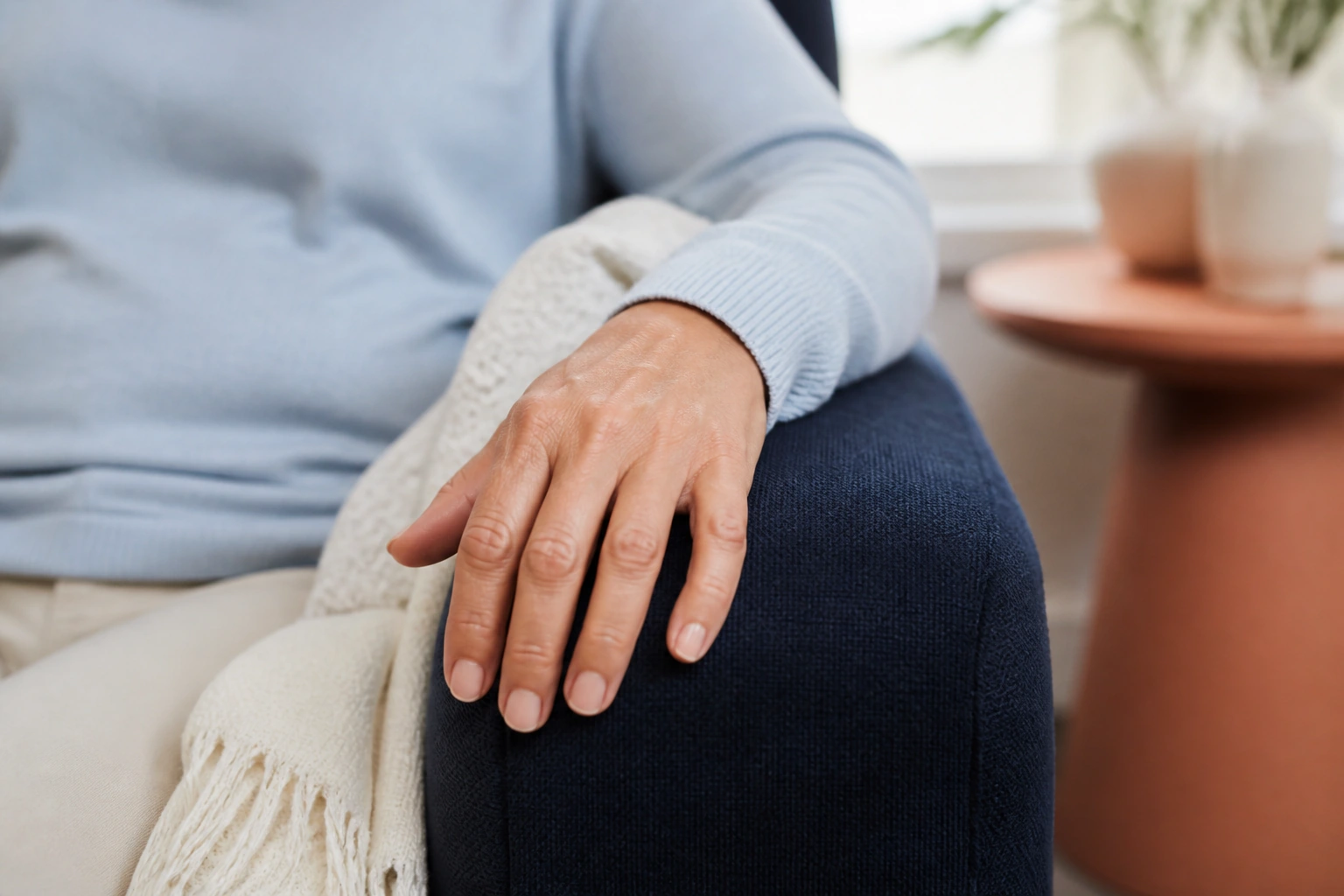 Close-up of a hand resting comfortably on a padded navy chair arm.