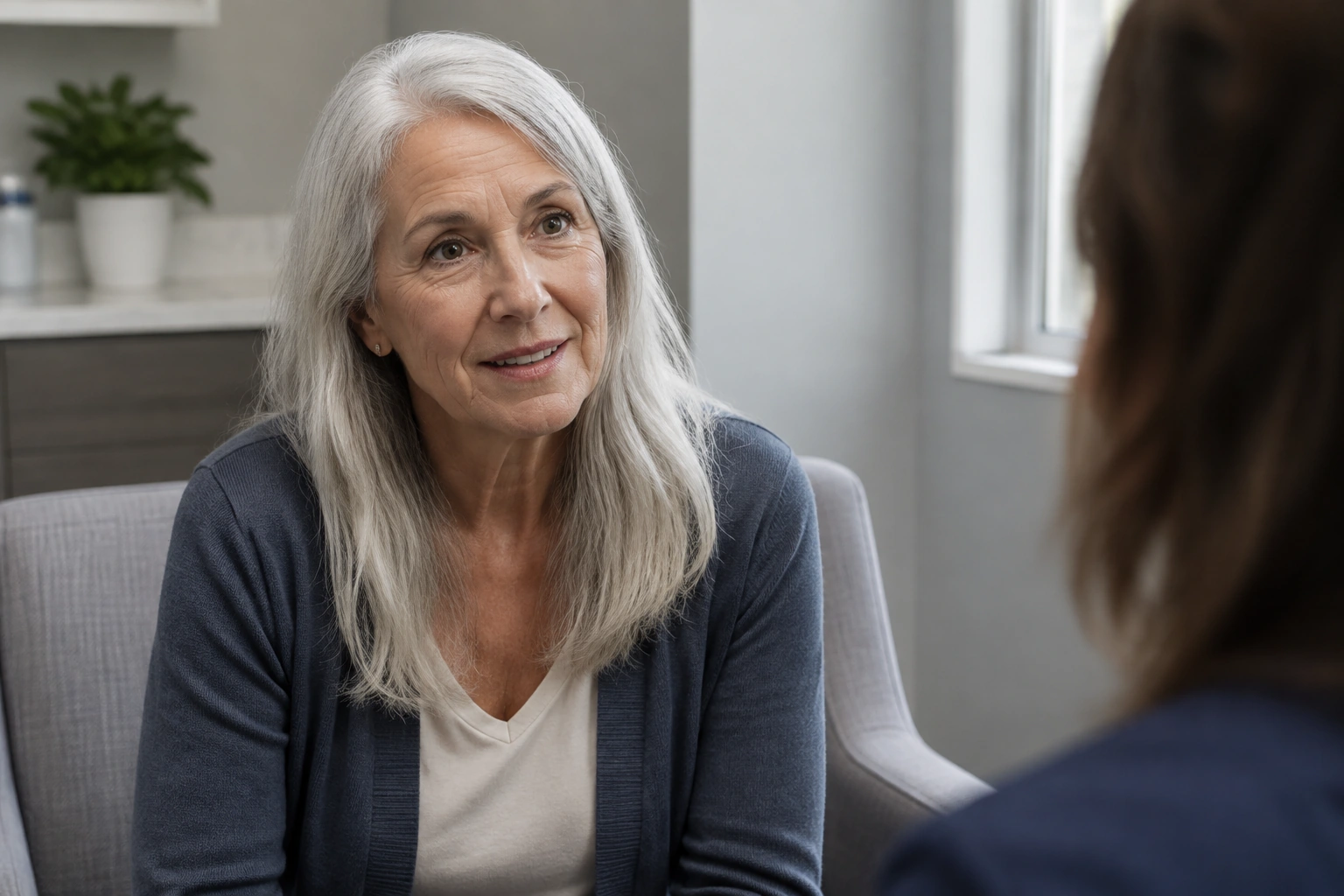 A mature woman with silver hair discussing a question with an off-camera clinician.